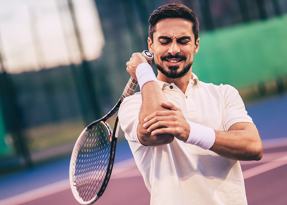 Male tennis player on the court, suffering from elbow pain while holding a racquet