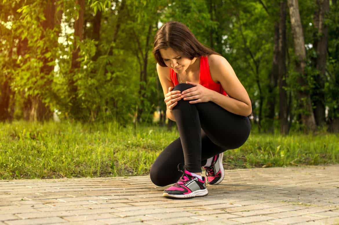 Woman in pain while running in park, knee injury, seizures