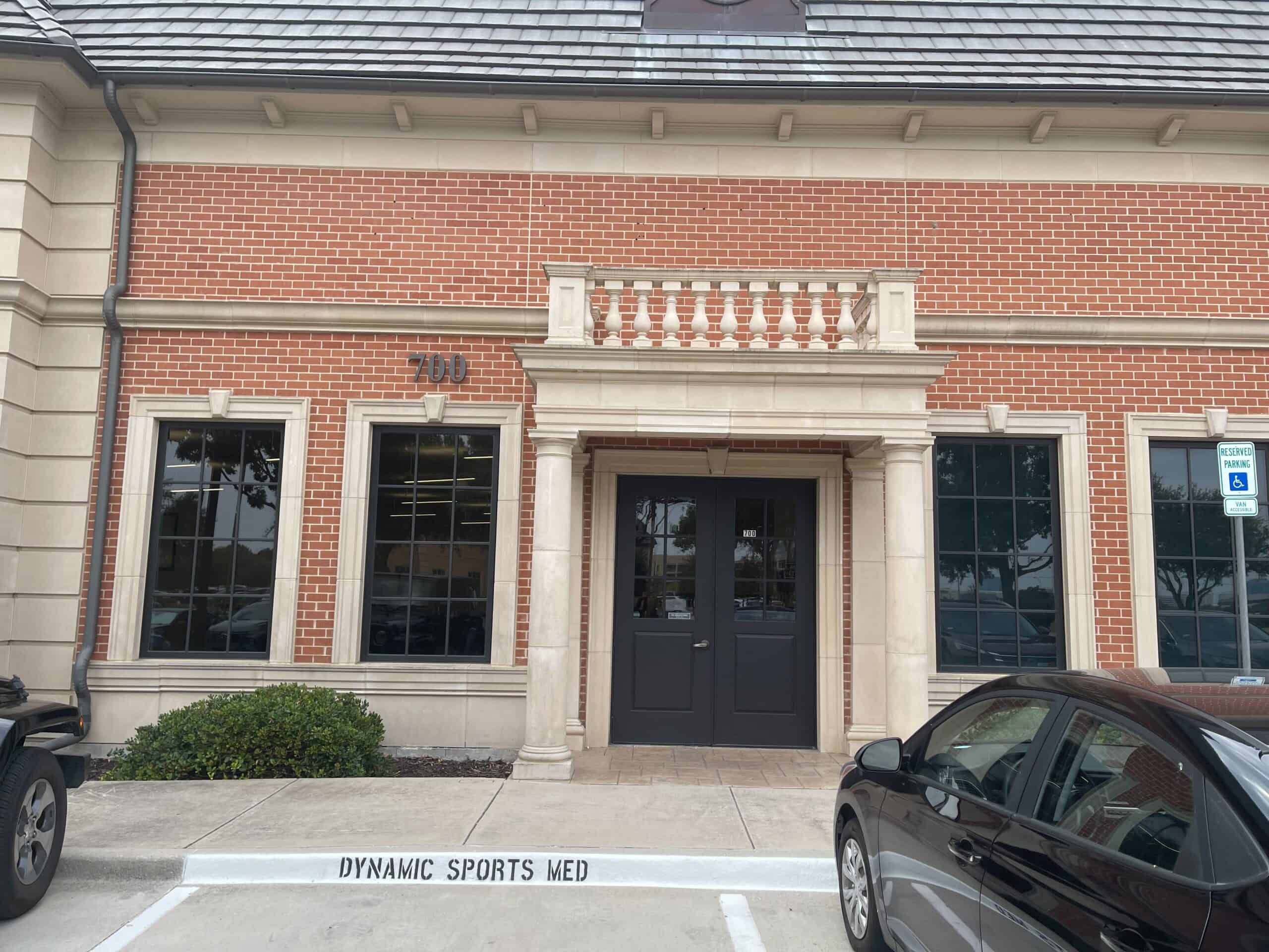 Therapeutic clinic exterior of Dynamic Sports Medicine in a renovated brick building with parking, specialized for sports injury treatment and sports medicine services in a professional healthcare environment.