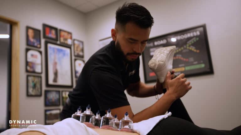 Sports medicine professional performing cupping therapy on an athlete for pain relief and recovery.