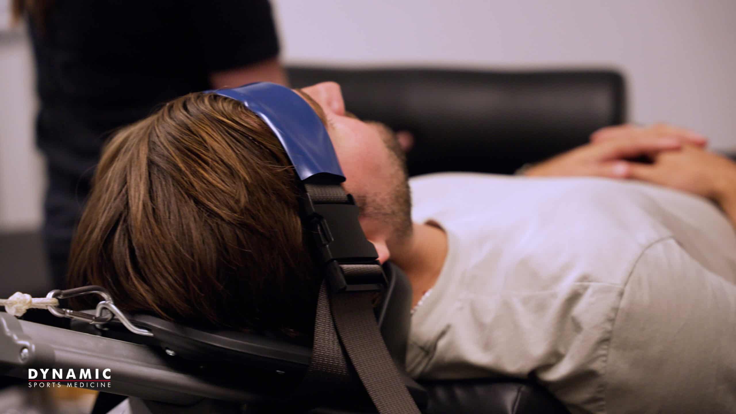 Person experiencing neck pain while sitting at a desk, highlighting the importance of ergonomic posture and sports medicine interventions for neck discomfort.