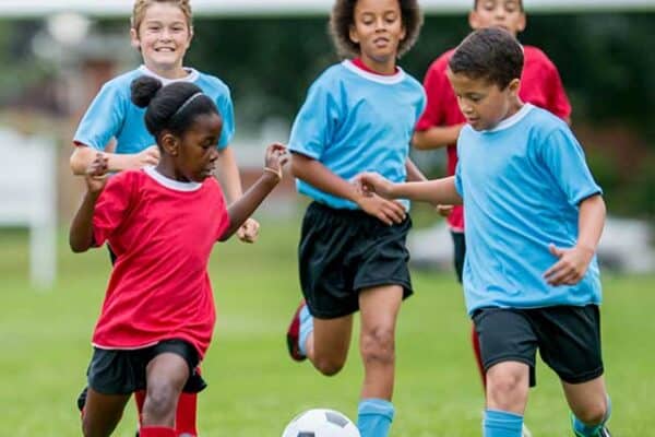 Group of children playing soccer outdoors, showcasing pediatric sports injury prevention and treatment at Dynamic Sports Medicine.