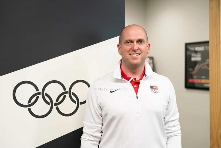 Olympic sports medicine specialist standing in front of the Olympic rings at Dynamic Sports Medicine clinic.