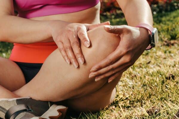 Close-up of a person experiencing knee pain, holding their knee outdoors, highlighting meniscus tear treatment options at Dynamic Sports Medicine.