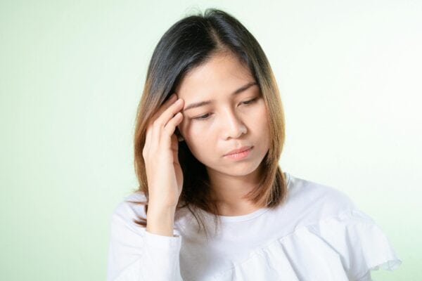 Young woman experiencing headache or dizziness, seeking concussion treatment at Dynamic Sports Medicine for recovery and management of sports-related head injuries.